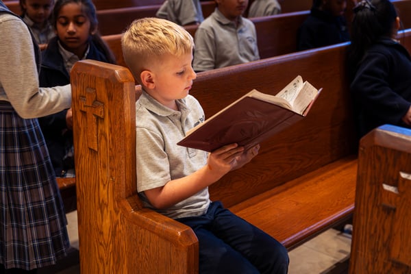 student in church pew with book